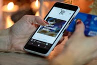 pexels-photo-230544-230544-2 Woman using smartphone for online shopping with credit card in hand, festive background lighting.